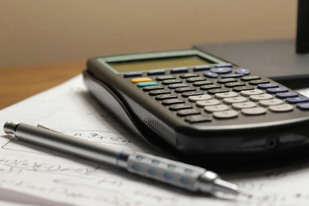 A calculator and pen resting on a page of notes