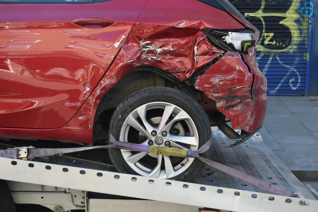 A car with a damaged rear panel loaded on a tow truck