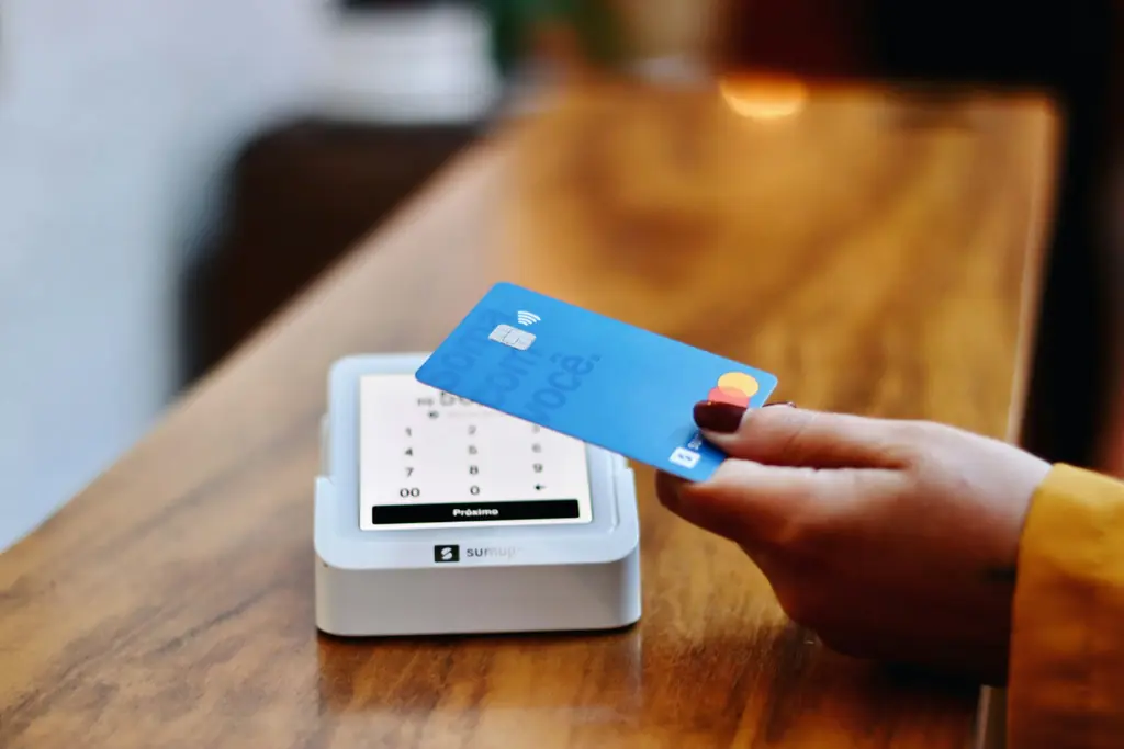 A card held over a payment reader on a timber table