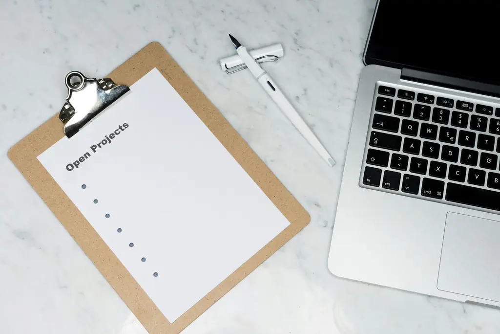 A clipboard with a checklist next to a laptop