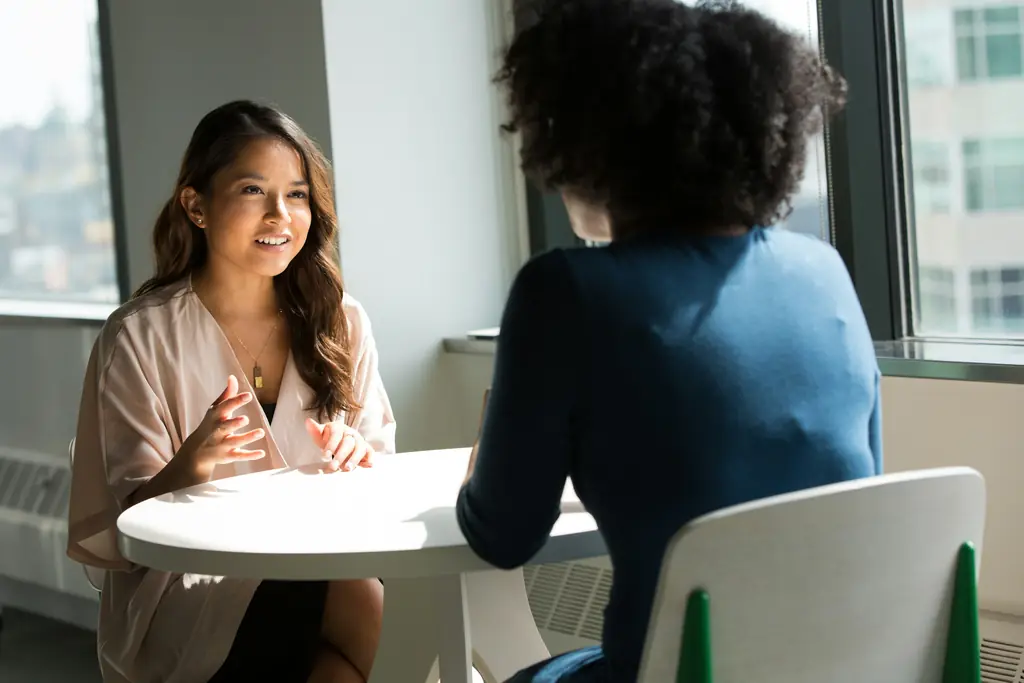 Two colleagues talking across a small round table