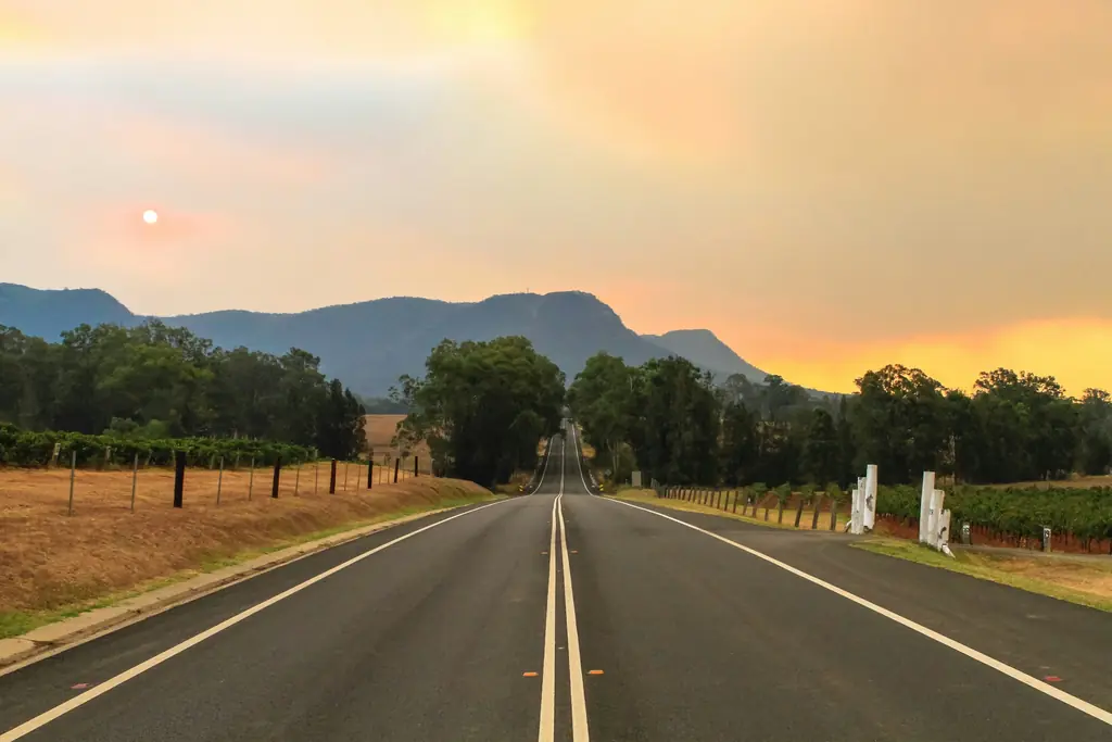 A country highway running toward hills at sunset