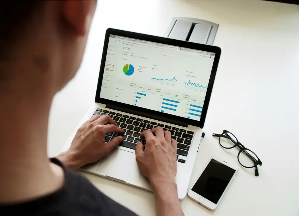 Hands typing on a laptop showing charts