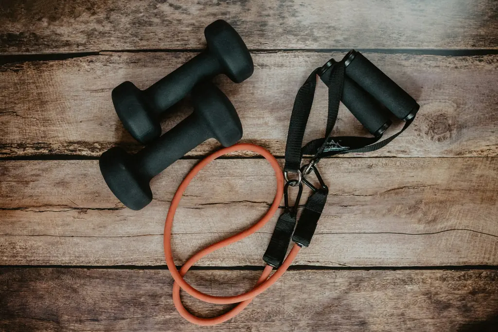 Two dumbbells and an exercise band on a timber surface