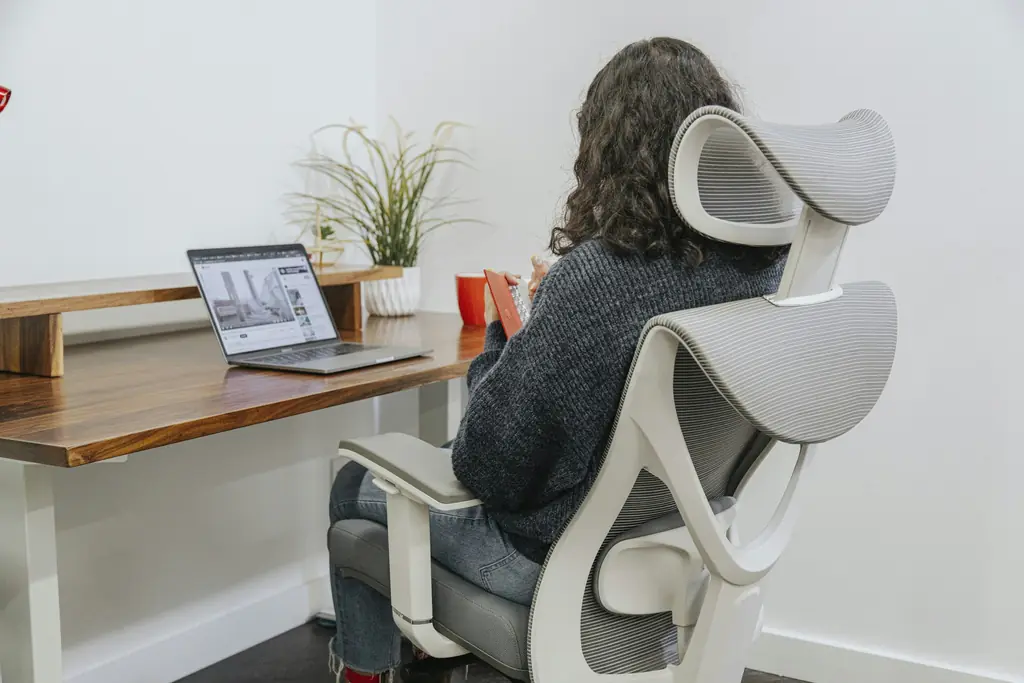 A person working at a height adjustable desk in an ergonomic chair
