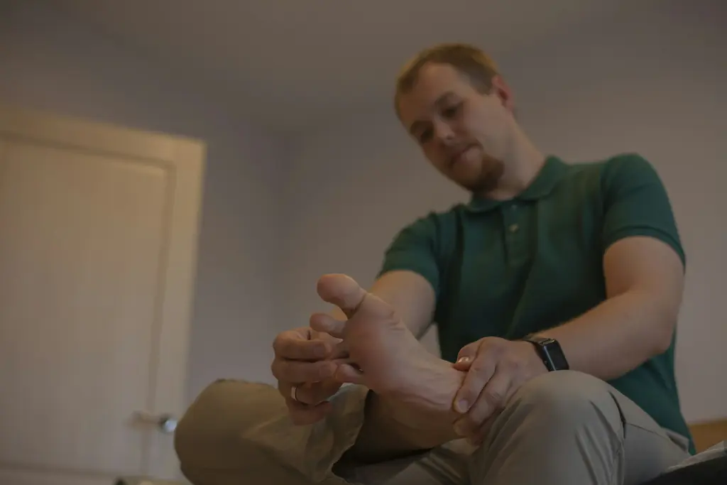 A man sitting down and holding his foot