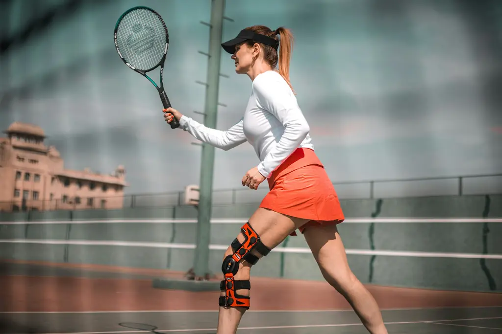 A tennis player wearing a knee brace mid swing
