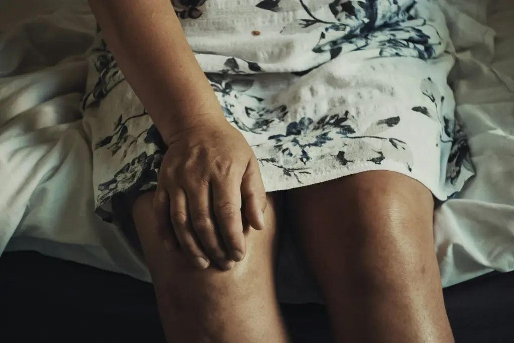 A person sitting with a hand resting on their knee