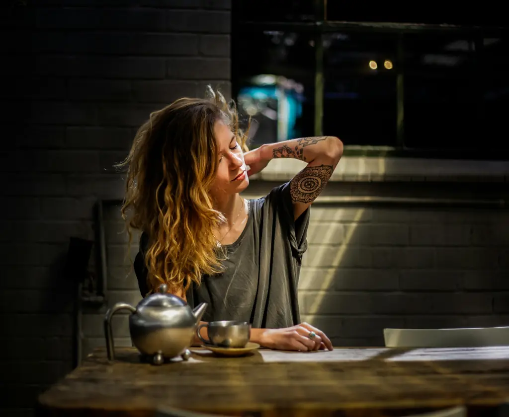 A woman at a table, holding her neck and stretching