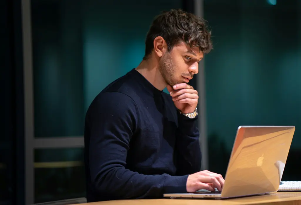 A man looking thoughtfully at a laptop