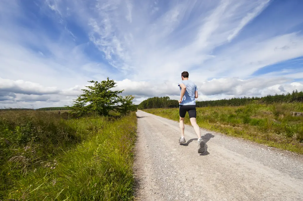 A runner on a gravel path through open countryside