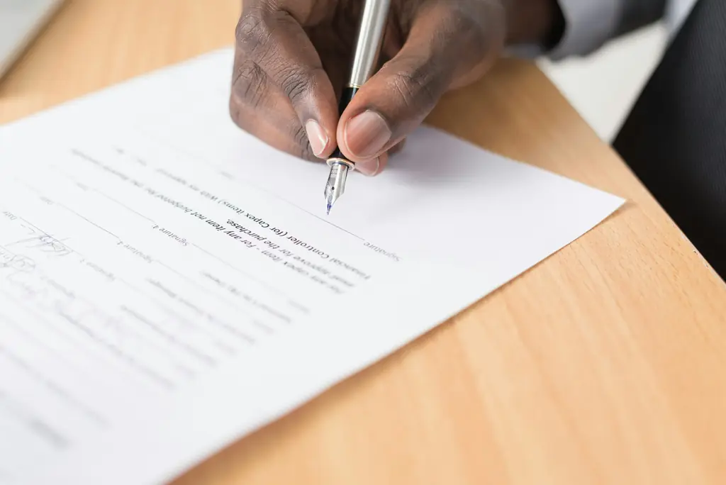 A hand signing a printed form