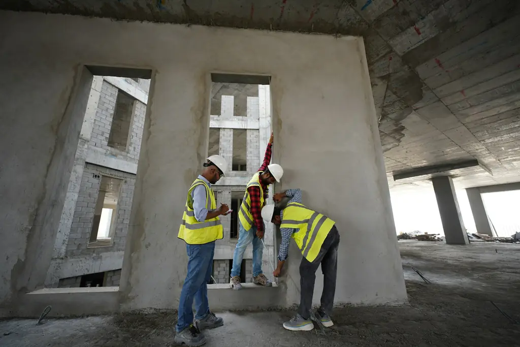 Three workers in high visibility vests talking inside a building under construction
