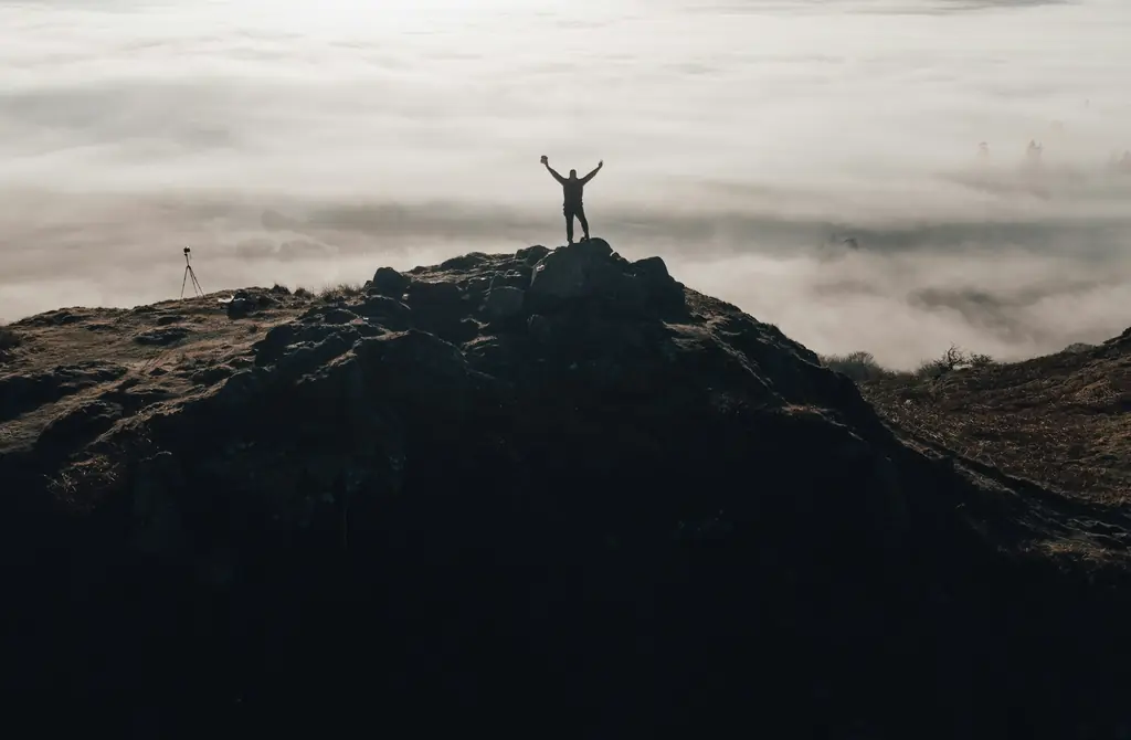 A person standing on a mountain top with arms raised